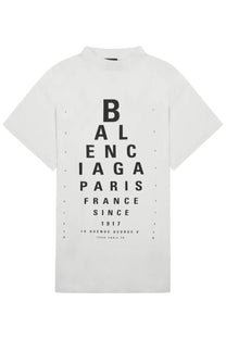 White Balenciaga women’s shirt featuring a bold black eye chart print with brand name and founding details