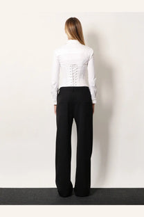 White corset-style blouse with lace-up back and long sleeves paired with Balenciaga black stretch wool trousers