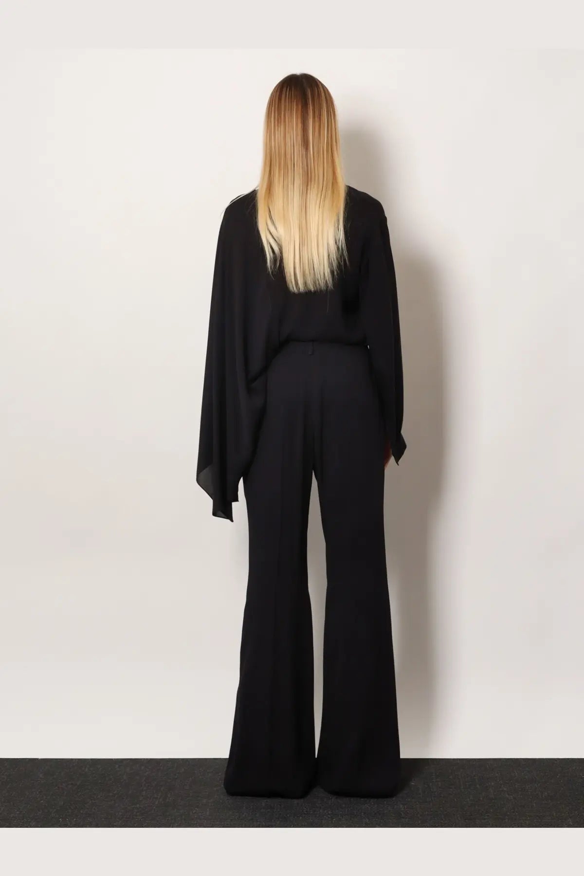 Balenciaga women’s black viscose wide-leg trousers paired with a flowing draped top from the front view