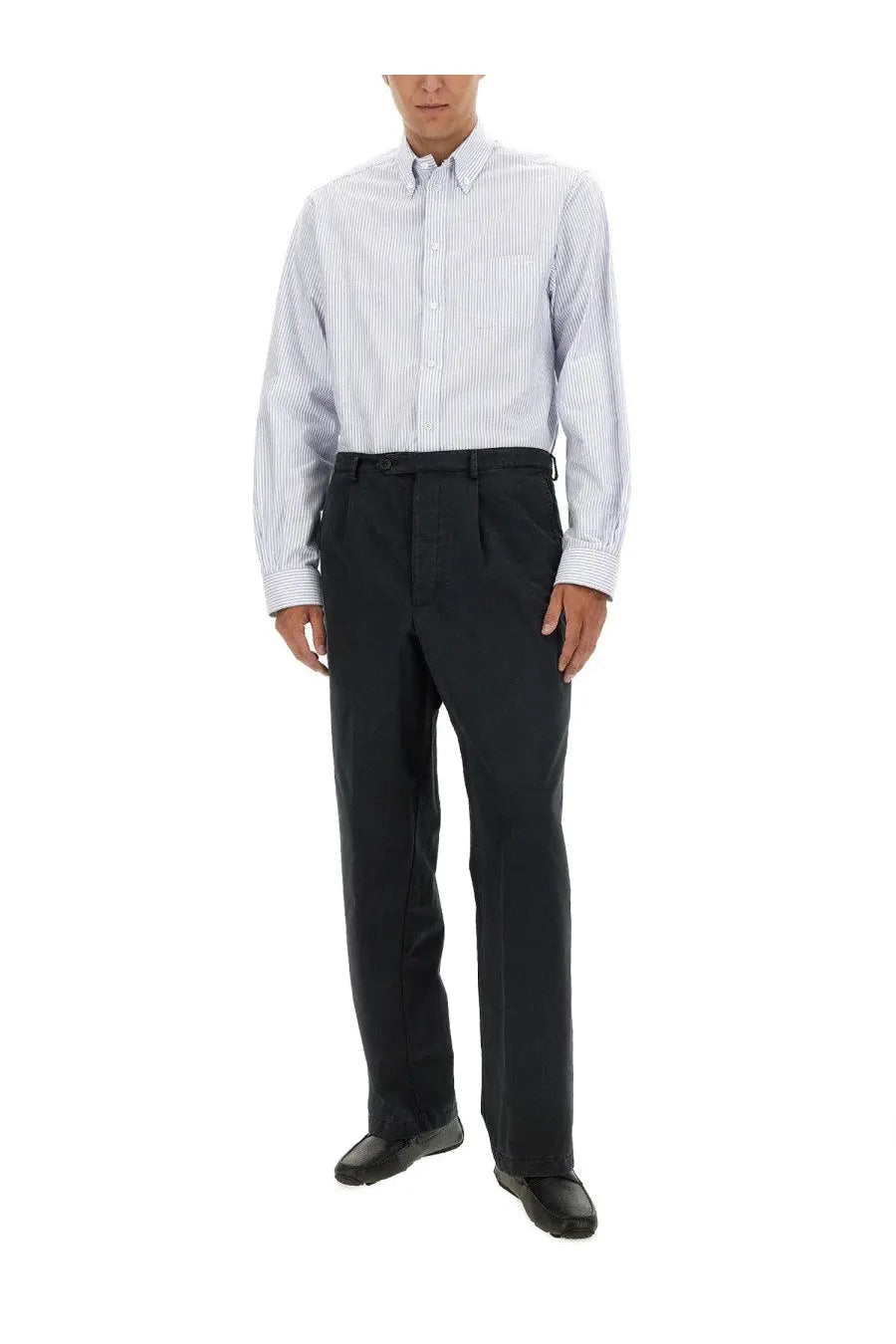 A man wearing a Bally men’s blue light blue and white striped button-down shirt with long sleeves and dark navy trousers