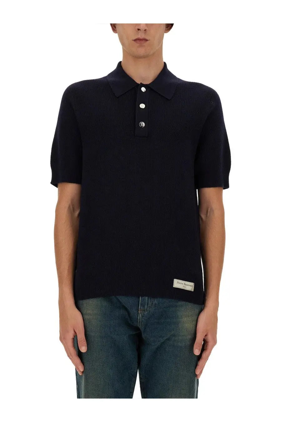 Balmain men’s black ribbed knit merino wool polo shirt with white buttons and small brand label at bottom hem