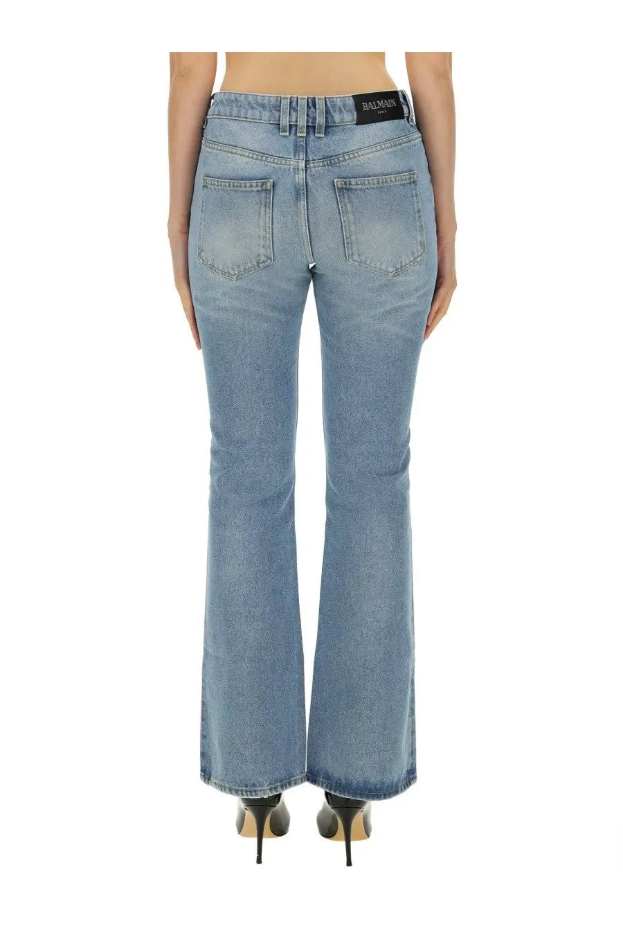 Back side view of balmain women’s blue light-wash denim flare jeans with classic pockets and black waistband label