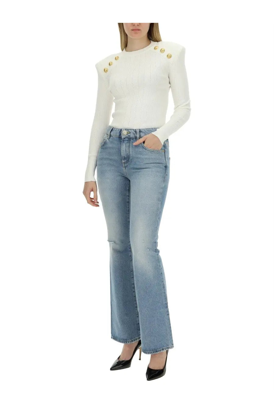 White long-sleeved top with gold button embellishments on shoulders paired with balmain women’s blue flare fit jeans