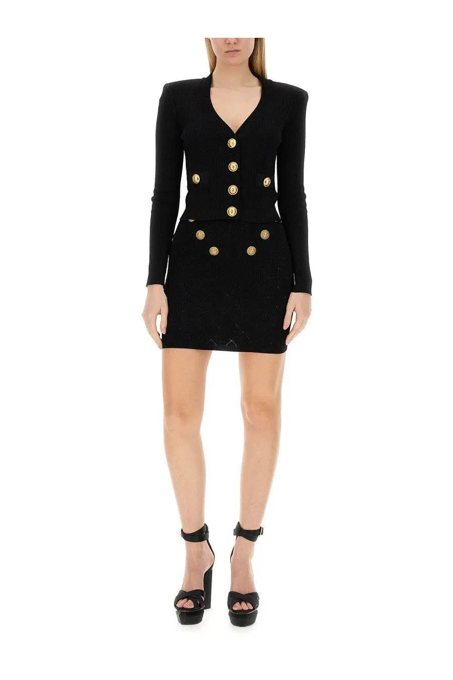 Black balmain knit skirt paired with a black double-breasted mini dress featuring gold-tone buttons and long sleeves