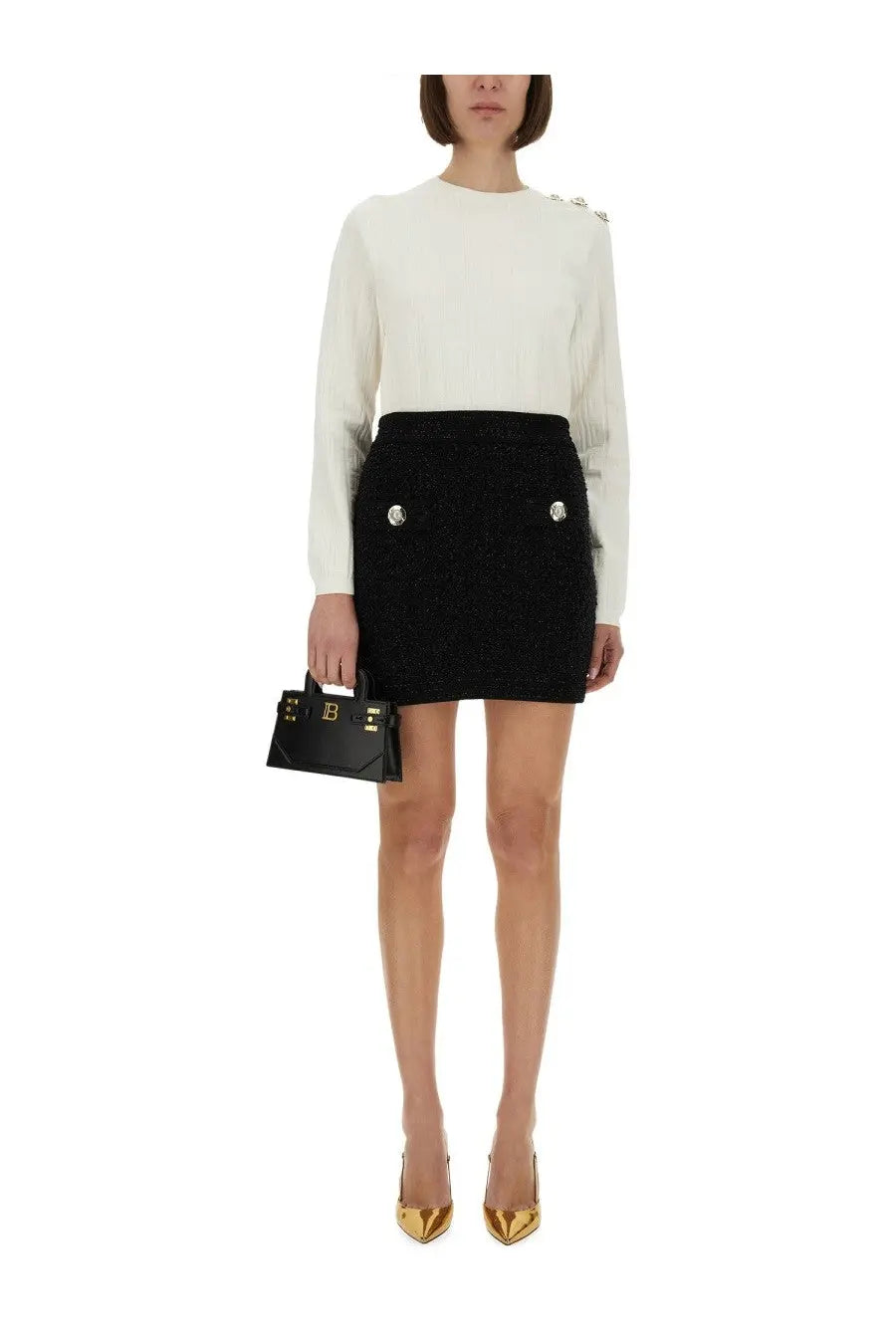Black textured mini skirt with silver button accents paired with balmain women’s white knitted top front view