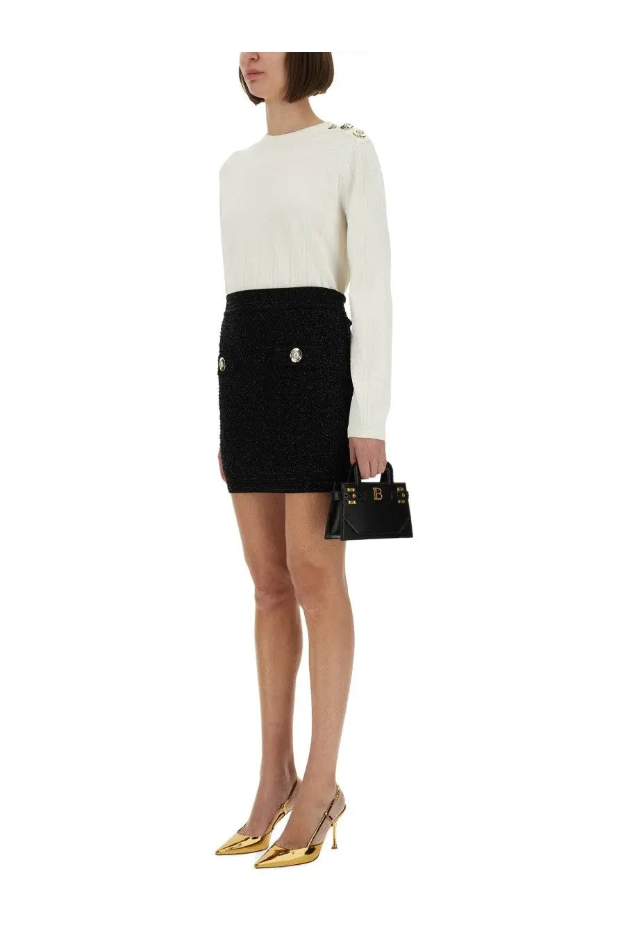 Black leather mini handbag with gold-tone hardware and structured rectangular design paired with Balmain black tweed skirt