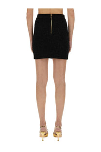 Back view of balmain women’s black tweed mini skirt with textured fabric and gold zipper detail