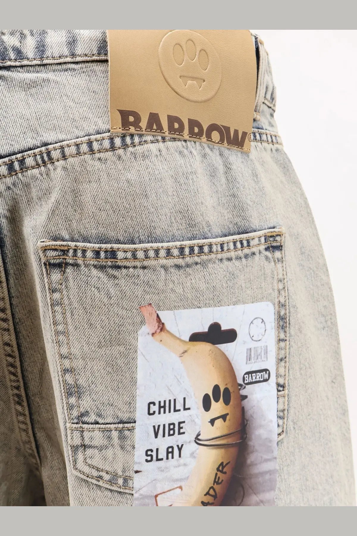 Light-wash barrow men’s cotton jeans with brown leather brand tag and paw print logo on the back waistband
