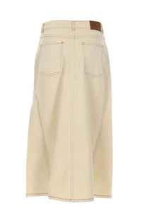 Beige denim midi skirt with two back pockets and brown leather brand patch at waistband shown from the back