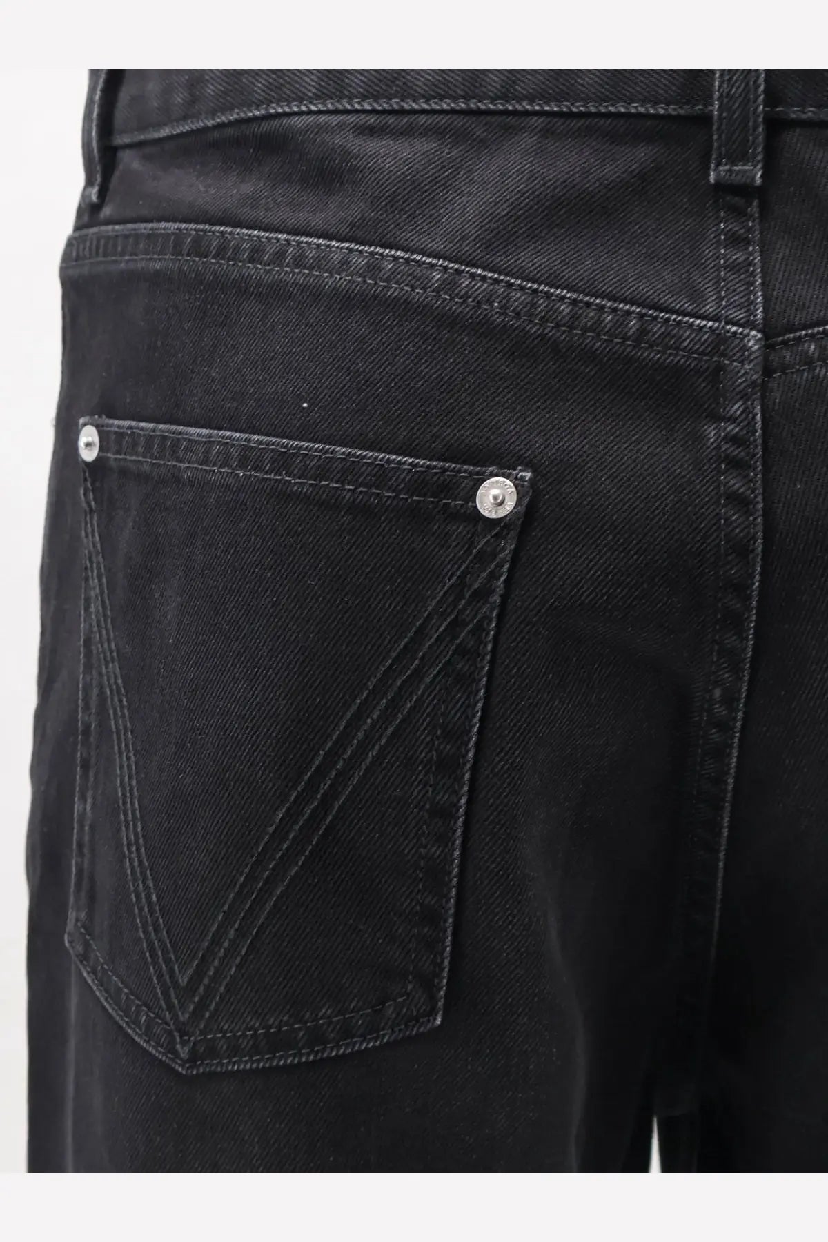 Back side of bottega veneta men’s black denim trousers showing classic back pocket with silver-toned button fastenings