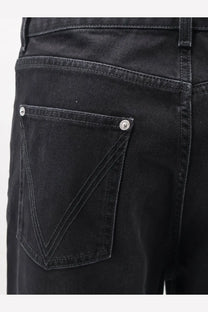 Back side of bottega veneta men’s black denim trousers showing classic back pocket with silver-toned button fastenings