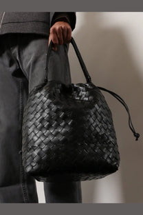 Bottega Veneta men’s bucket leather shoulder bag in black with woven intrecciato pattern and drawstring closure