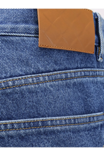 Blue denim jeans with a tan leather patch on the waistband showing the back side from bottega veneta men’s collection