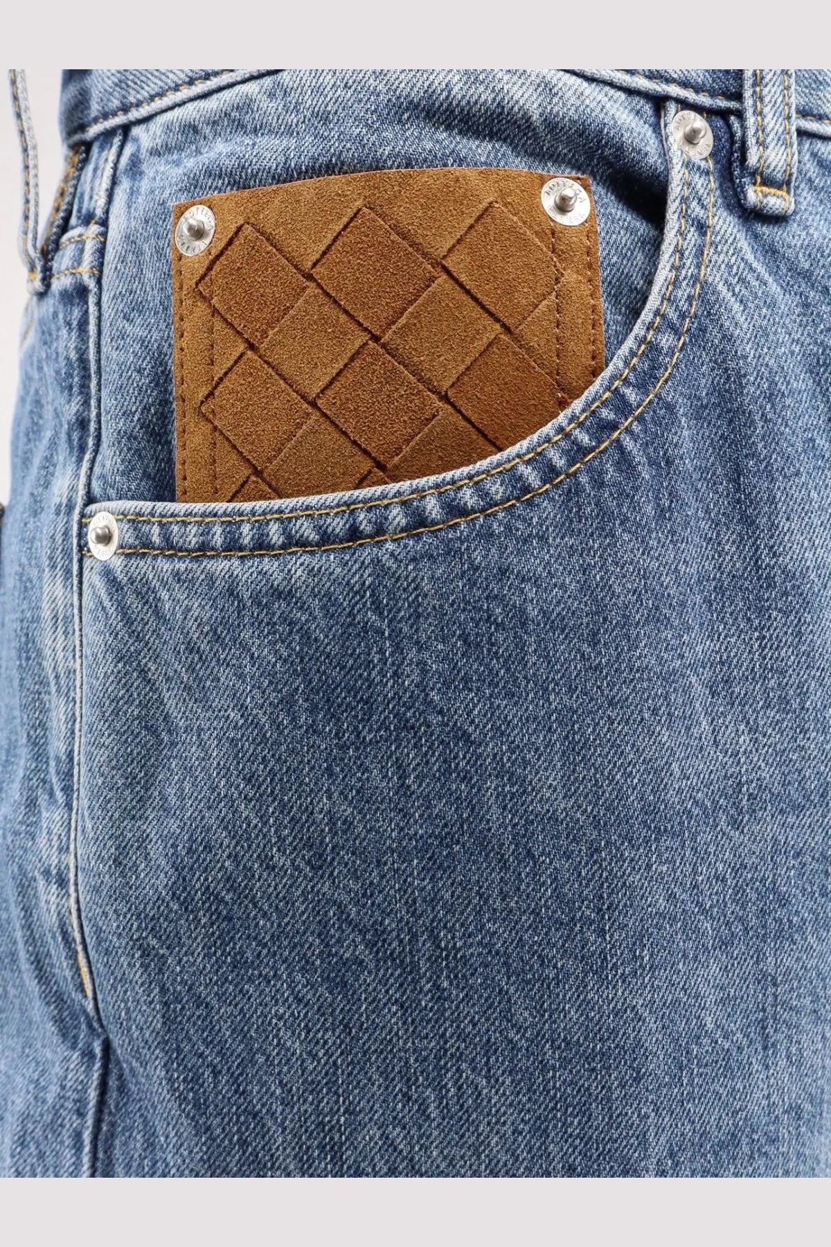 Brown woven leather patch with silver studs and diamond pattern on back of bottega veneta men’s wide leg blue jeans