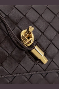 Black woven leather clutch with gold-tone knot clasp pairing with bottega veneta andiamo crossbody brown bag