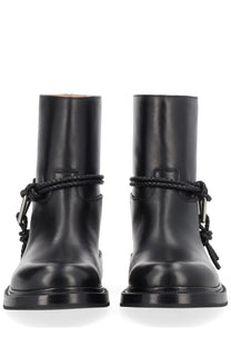 Bottega Veneta women’s black leather ankle boots with braided cord detailing and metal buckles visible from the back