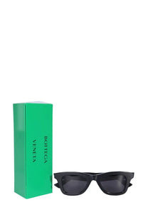 Black rectangular-frame bottega veneta women’s classic sunglasses with dark lenses next to a green box