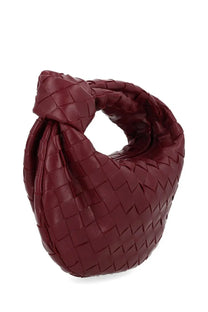A deep burgundy bottega veneta women’s mini jodie bag made of intrecciato leather with a distinctive knot design