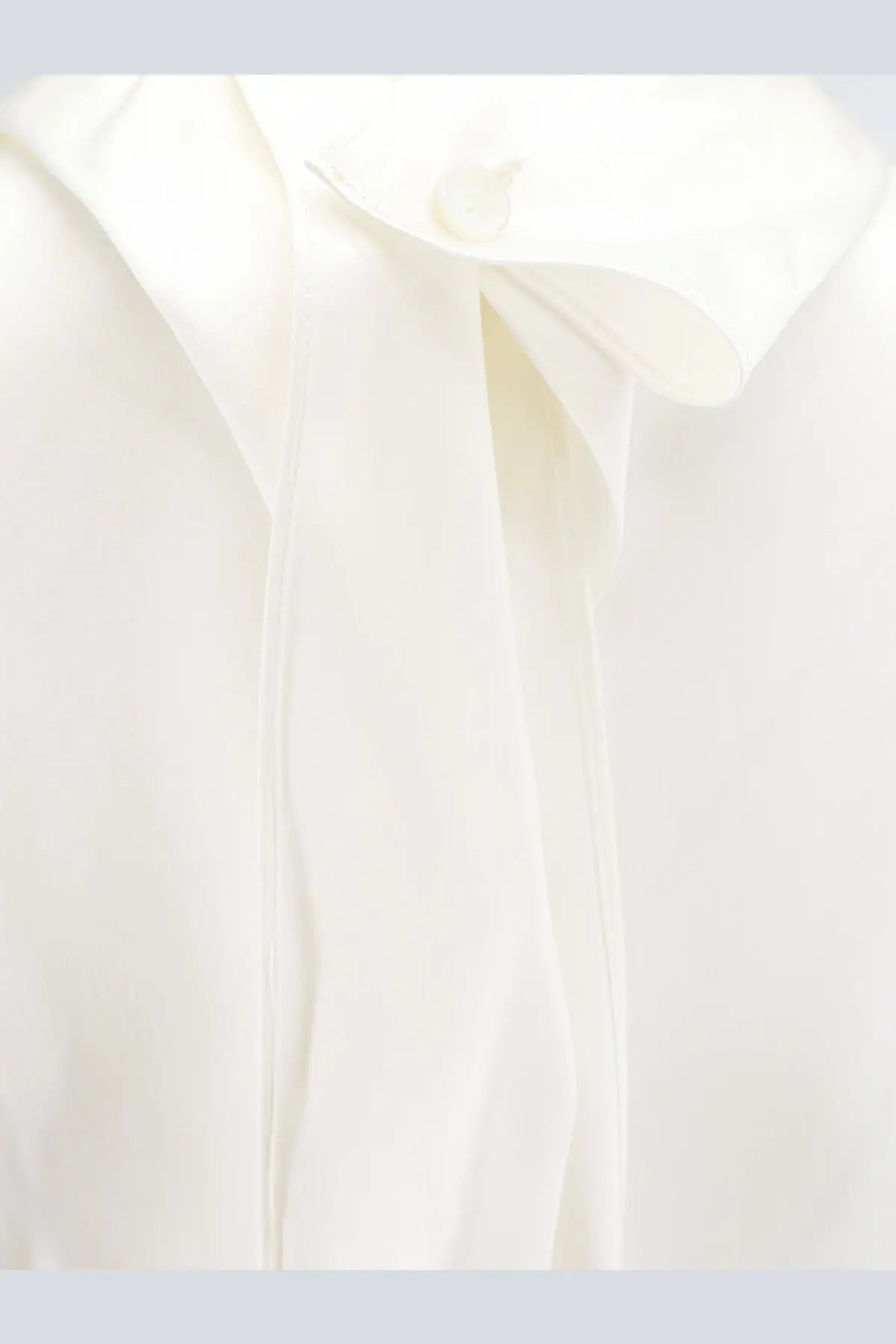 A crisp white silk blouse by Bottega Veneta with a classic collar and subtle front pleats in stretch satin