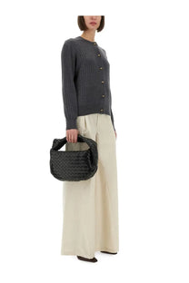 Black woven leather bottega veneta handbag with structured rounded shape and top handle shown with grey wool cardigan