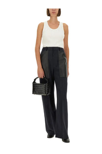 Black woven leather mini handbag with structured rectangular shape and top handle paired with bottega veneta blue wool cotton pants