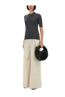 Black woven bottega veneta handbag with distinctive knot handle complementing women’s wool jersey grey outfit