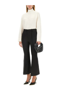 Black textured woven handbag with a distinctive twisted knot handle paired with bottega veneta women’s wool pants black