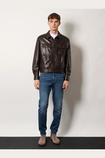 A sleek dark brown leather jacket with classic collar and front flap pockets paired with Brunello Cucinelli men’s blue cotton jeans