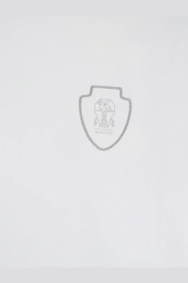 Silver shield-shaped emblem with central trophy and engraved text on brunello cucinelli men’s white technical fabric shirt
