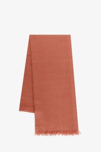 A soft terracotta-colored Brunello Cucinelli women’s cashmere and silk scarf with textured weave and fringed edges