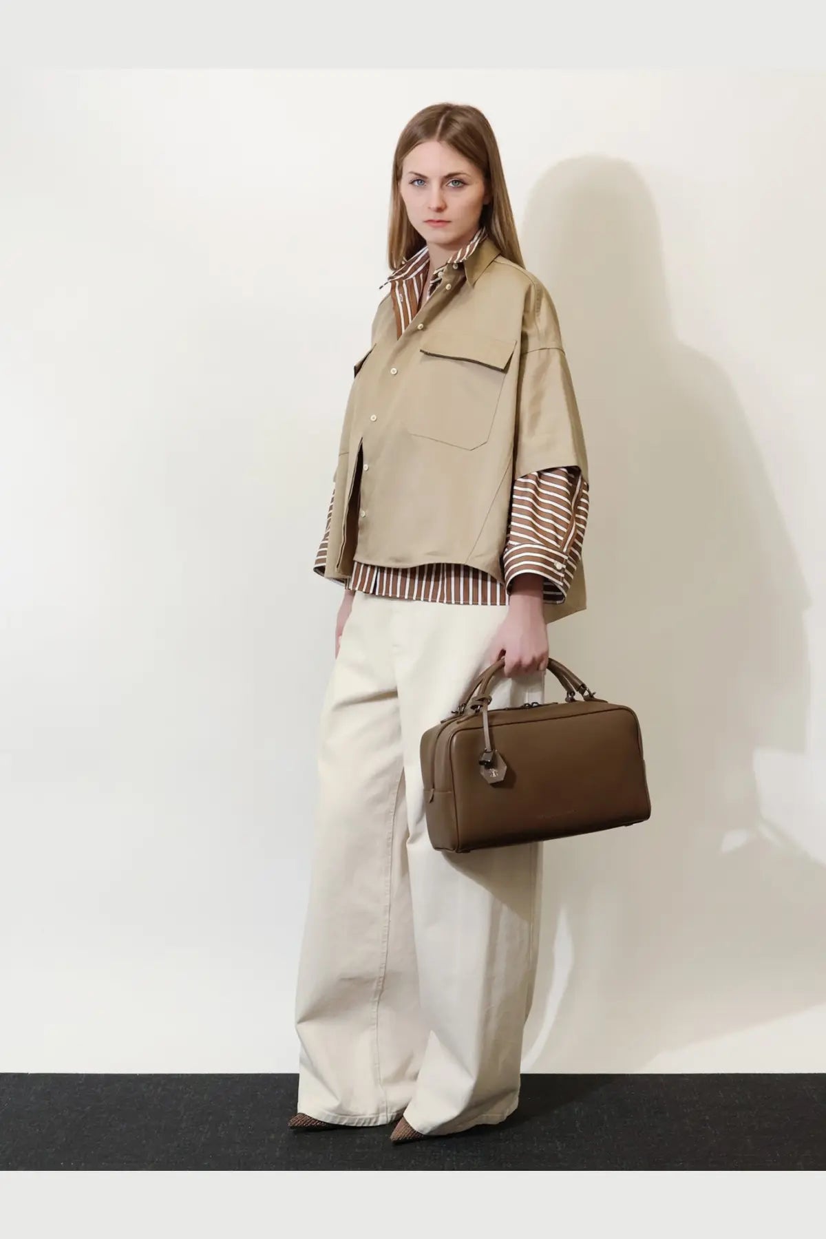 Brown leather briefcase with top handle and small metal clasp shown alongside brunello cucinelli beige linen and cotton blend shirt