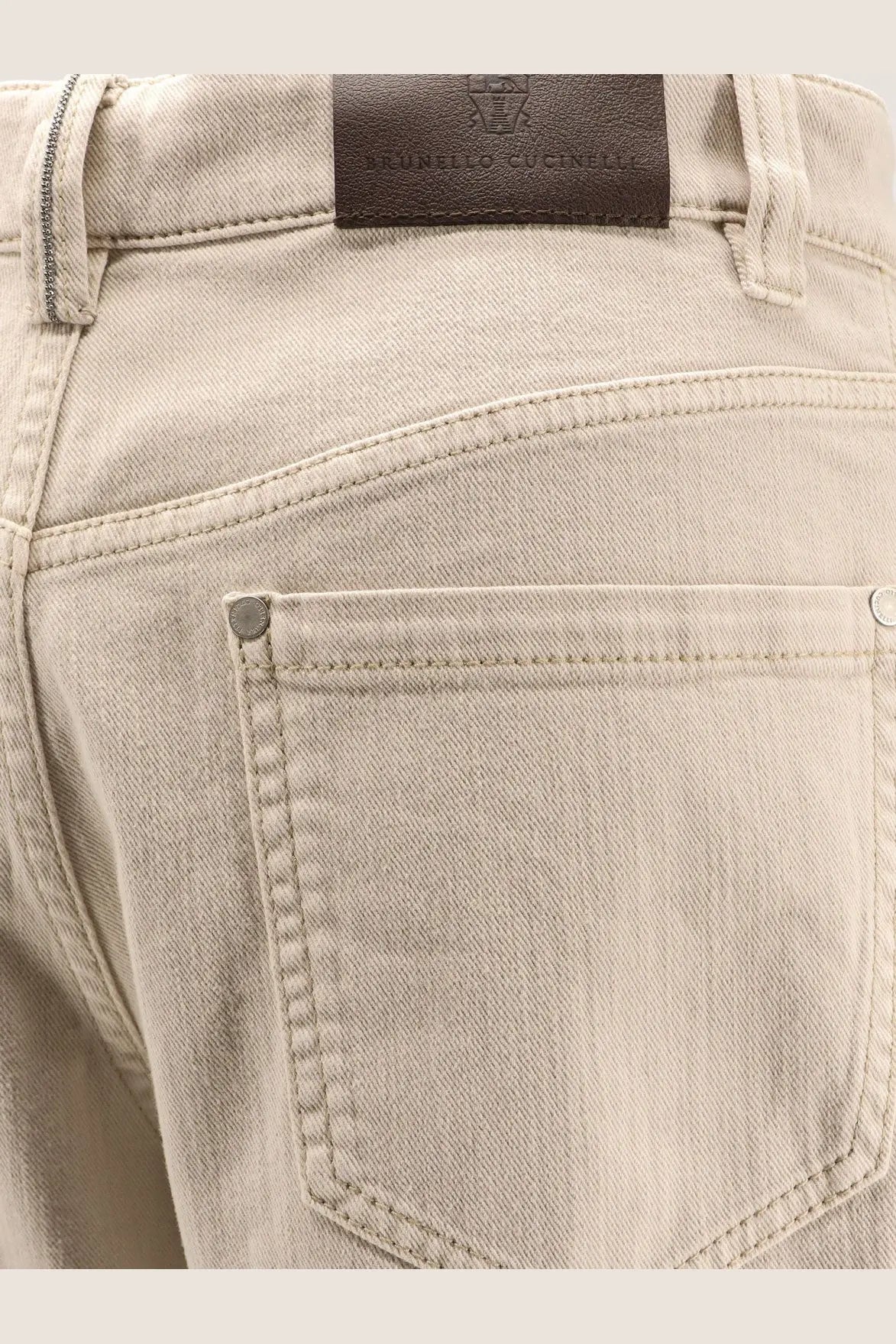Beige denim Brunello Cucinelli women’s loose barrel jeans with brown leather brand patch at the waistband back side