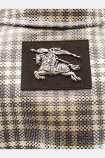 Burberry men’s foxfield madras trench white with silver embroidered knight patch on dark brown leather and plaid fabric background