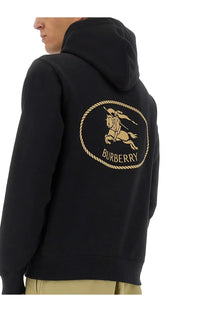 Black Burberry men’s hoodie featuring a gold embroidered horse and rider logo within an oval rope border