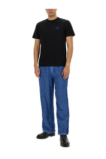 Black short-sleeved t-shirt with small embroidered blue logo on left chest paired with Burberry men’s blue linen pants