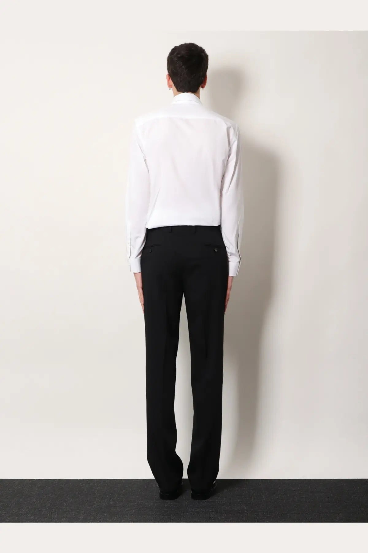A man wearing a Burberry men’s Sam organic cotton shirt white paired with black tailored trousers