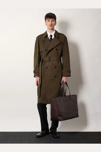 Olive green double-breasted trench coat with black belt and dark brown leather handles paired with burberry men’s white organic cotton shirt
