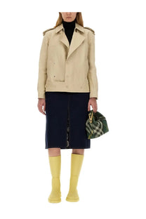 Beige trench coat with shoulder pads and button closures paired with burberry women’s mini peg bag green