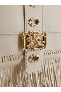 Cream-colored Burberry Womens Rider leather handbag with gold metal clasp embossed with knight on horseback design and braided detailing