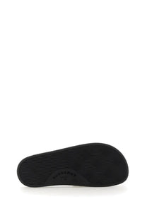 Black rubber sole of burberry women’s beige slide sandal shown from the back side
