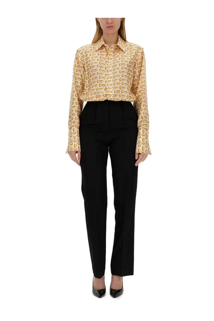 A woman wearing a beige Burberry women’s long-sleeved shirt with gold lettering all-over pattern