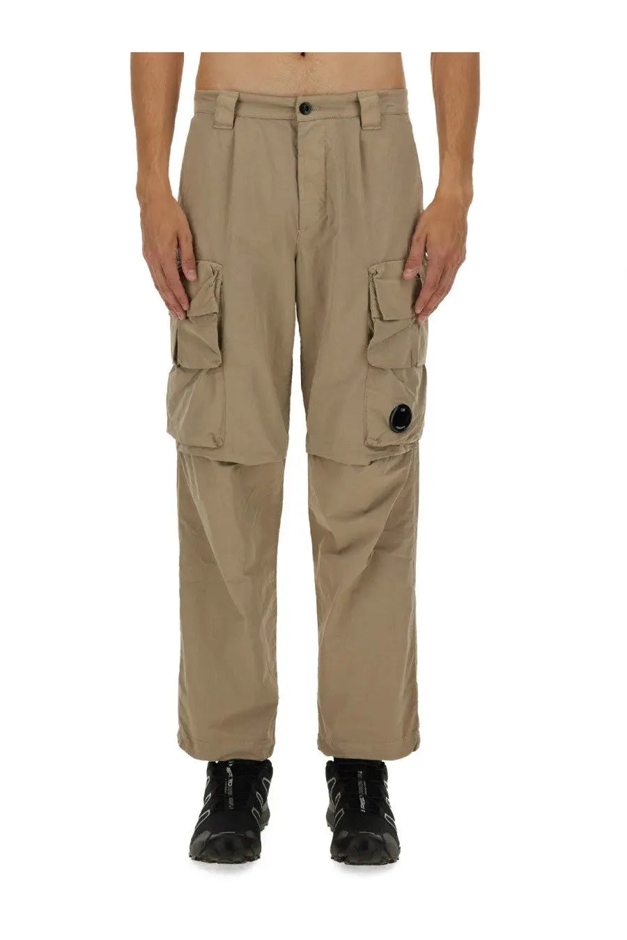 C.p. company men’s beige cargo pants featuring multiple flap pockets and a black circular logo on the right thigh