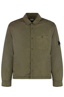 Olive green quilted button-up jacket with chest pocket and black circular logo patch on left sleeve by c.p. company