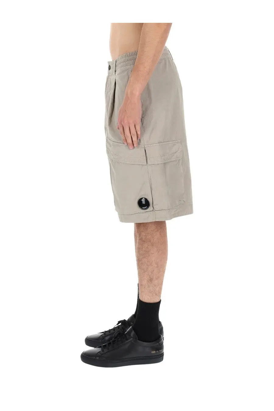 Beige c.p. company men’s cargo shorts with multiple pockets and a black circular side button in grey con patch style