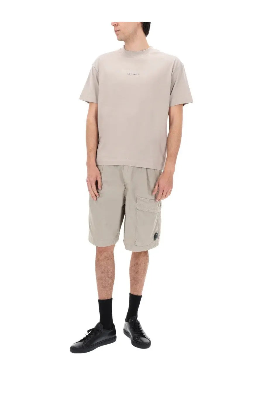 Beige short-sleeved t-shirt with subtle logo on chest paired with grey c.p. company men’s shorts cargo con patch