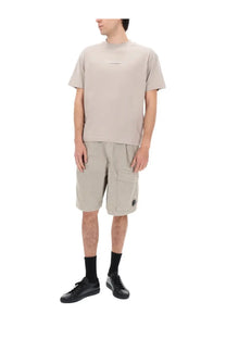 Beige short-sleeved t-shirt with subtle logo on chest paired with grey c.p. company men’s shorts cargo con patch
