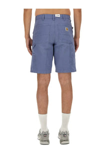 Back view of carhartt wip men’s columbia blue cargo bermuda shorts with multiple pockets and yellow logo patch