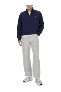 Navy blue carhartt wip half-zip sweatshirt with yellow logo paired with men’s white cargo pants