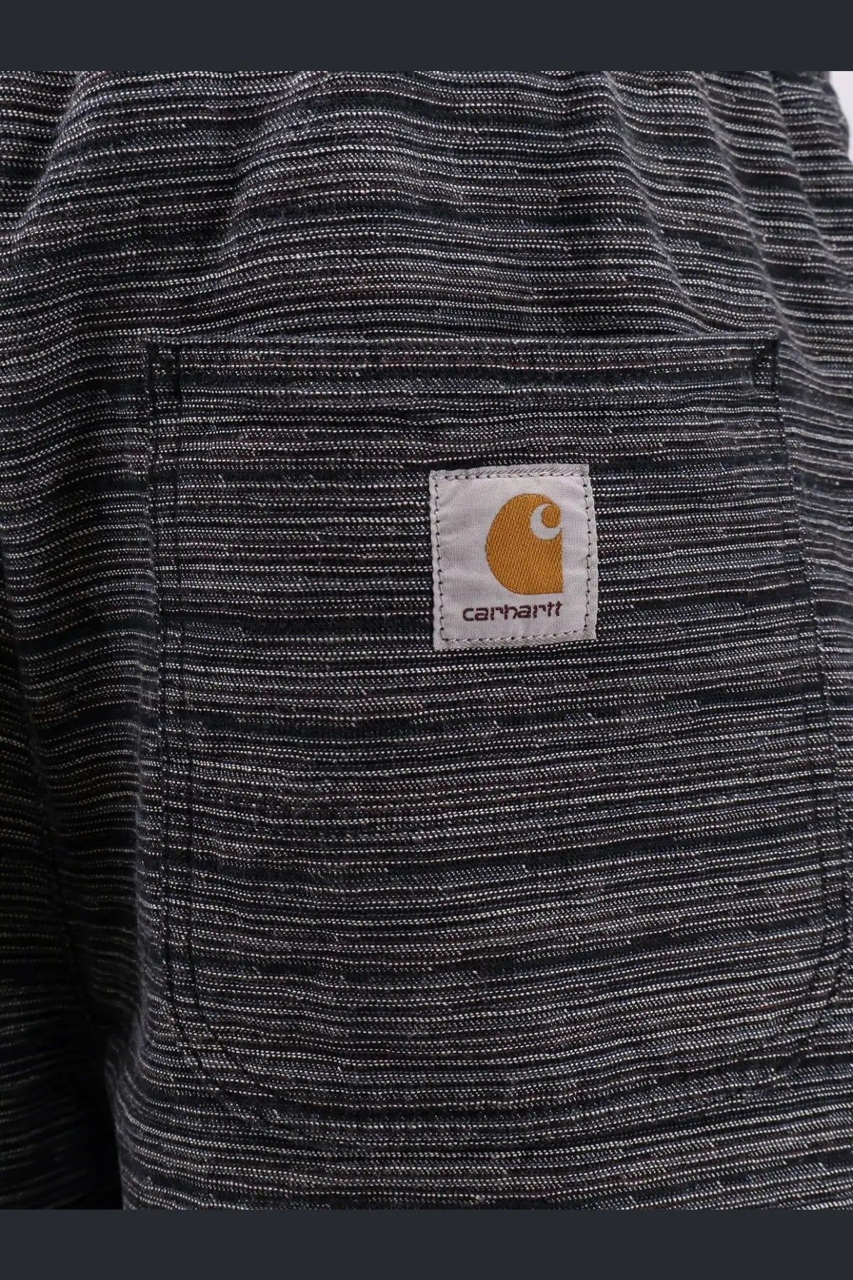 Black and white striped carhartt work shirt with tan logo patch on chest pocket paired with relaxed fit shorts