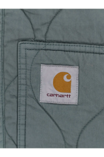 A white carhartt patch with yellow logo and purple text sewn on quilted gray fabric of carhartt wip men’s kylan liner cotton jacket green